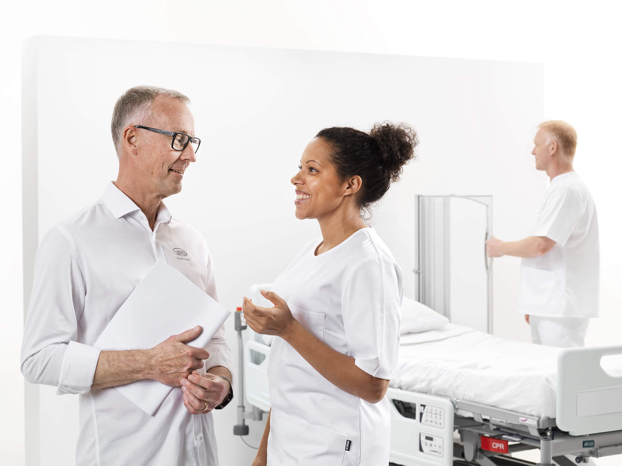 Silentia sales advisor and smiling nurse talking by a hospital bed, illustrating a supportive partnership.