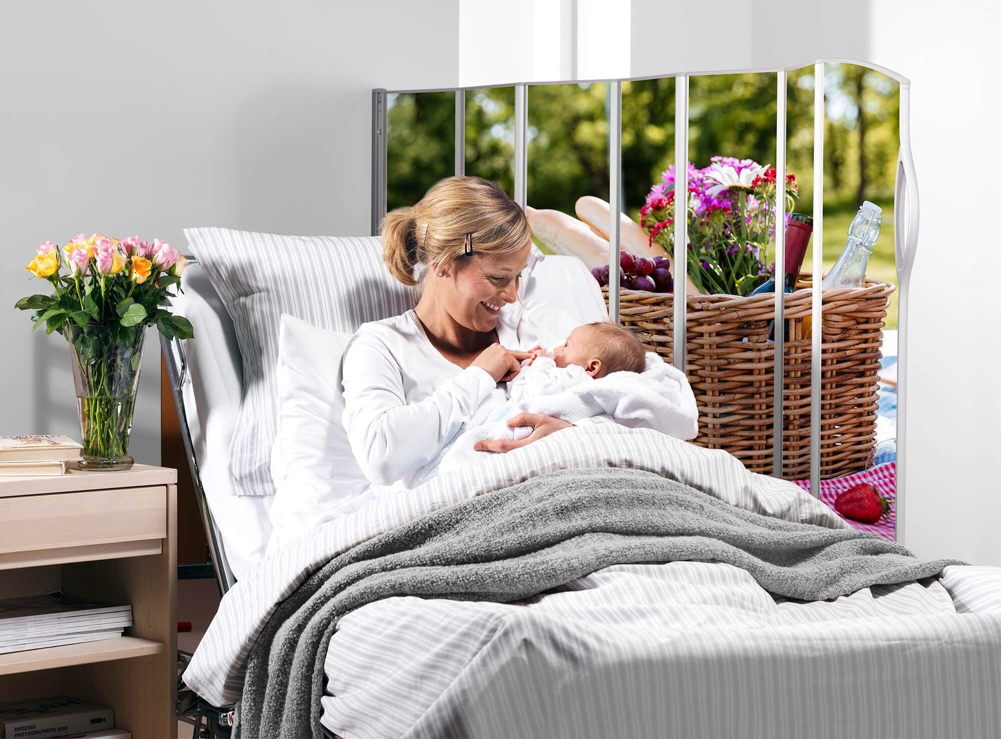 Mother cradling her baby in bed beside a Silentia screen printed with the Picnic 2 PhotoPanels™ image.