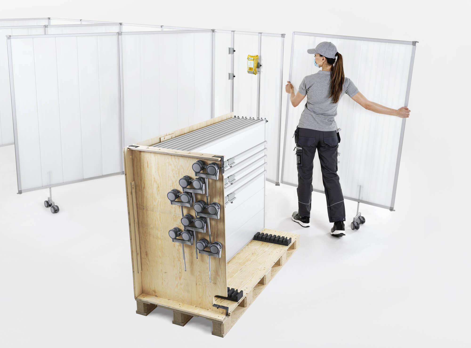 Monteur die Silentia PopUp-schermen assembleert, met wielen en rails verpakt op een pallet.