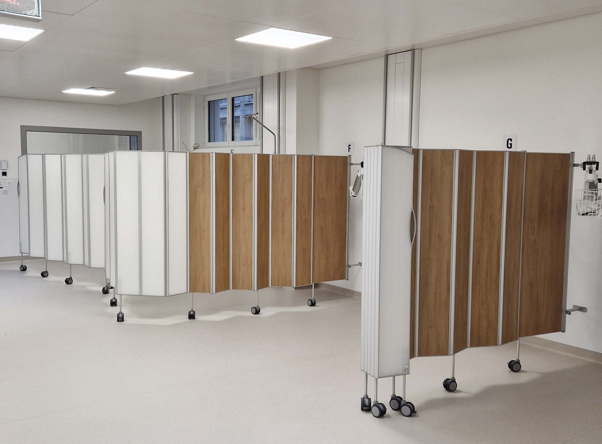 Silentia Add-Faltwände mit weißen und holzfarbenen Platten entlang eines Krankenhauszimmers.