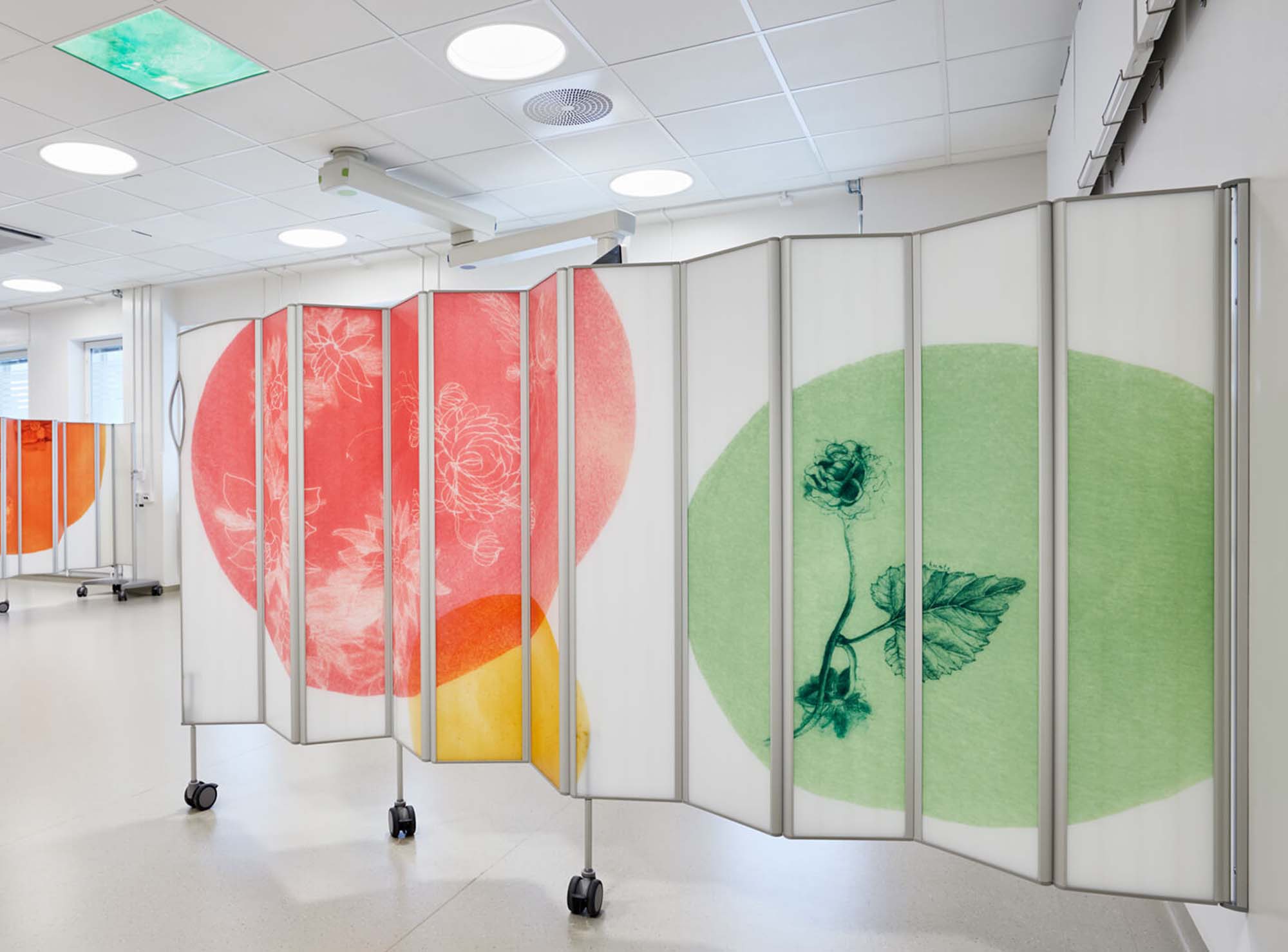 Korridor avskärmad med Silentia Fold PhotoPanels™ tryckta med röda och gröna blomstercirklar.