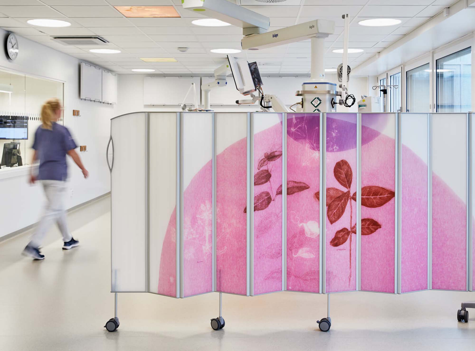 Silentia Fold screen with pink floral PhotoPanels™ dividing a Södersjukhuset ward as a nurse passes.