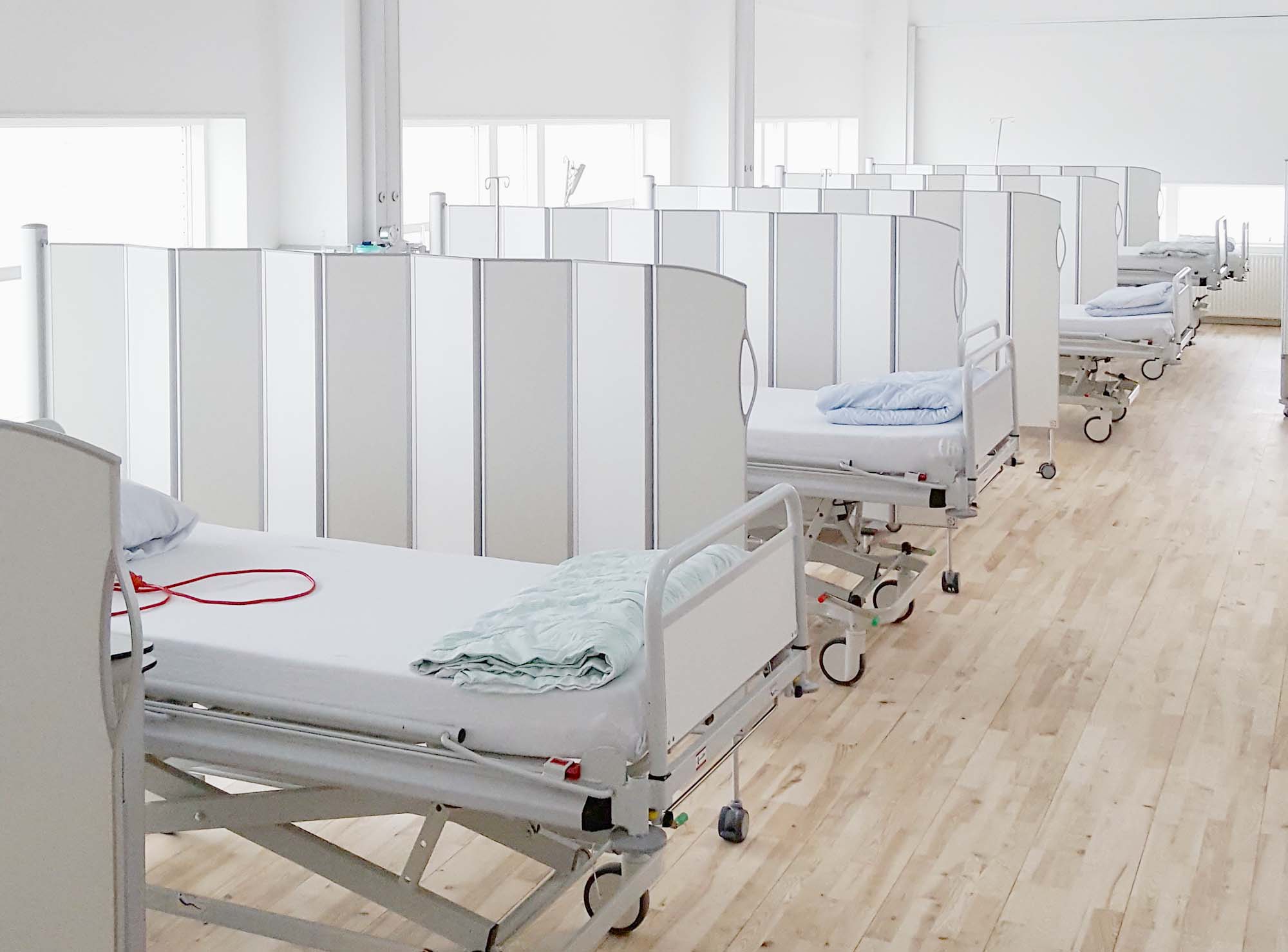 White Silentia Fold screens dividing rows of hospital beds across a large open care space.