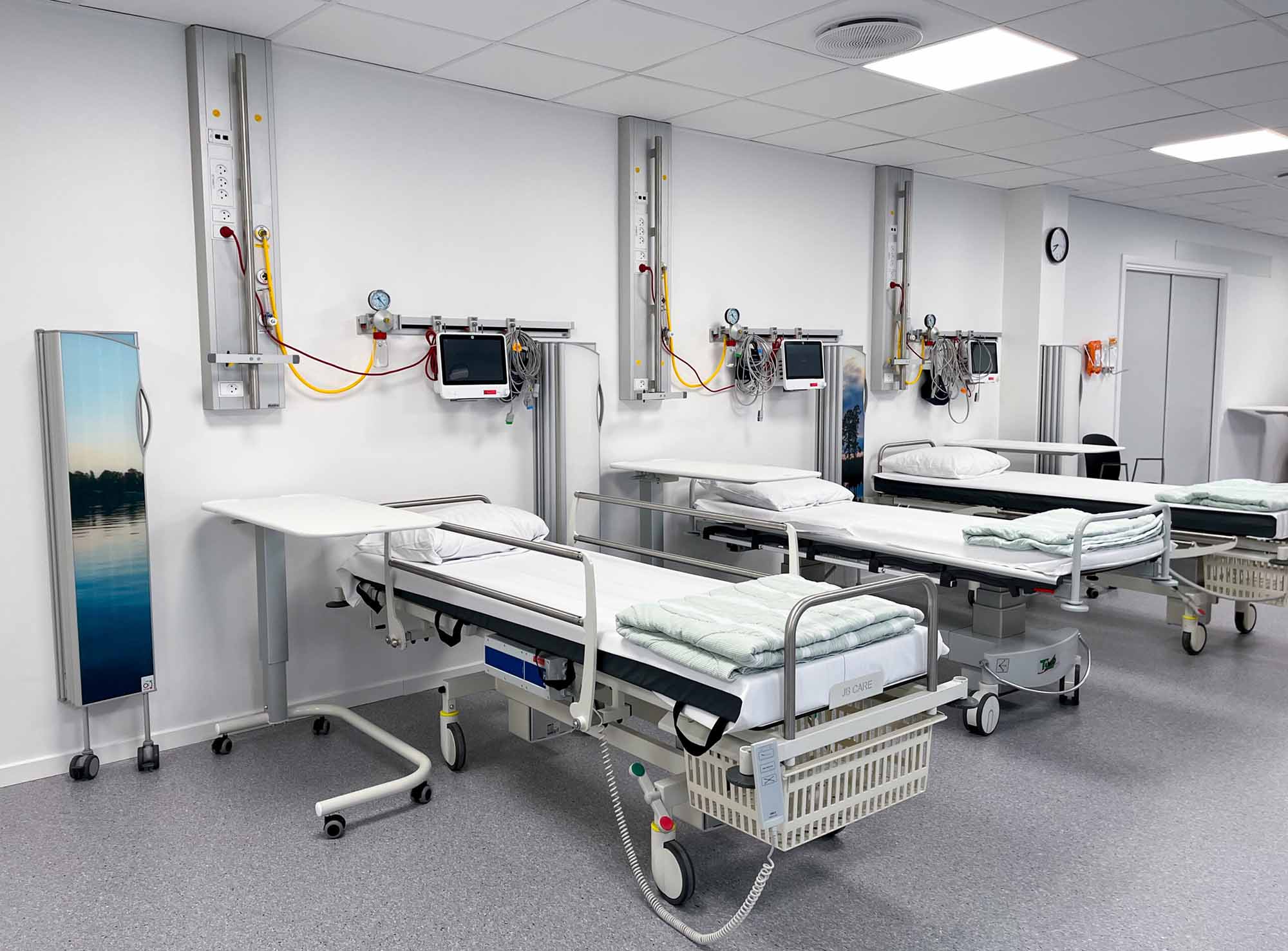Silentia Fixed wall-mounted screen with a calm lake image beside beds in an open care space.