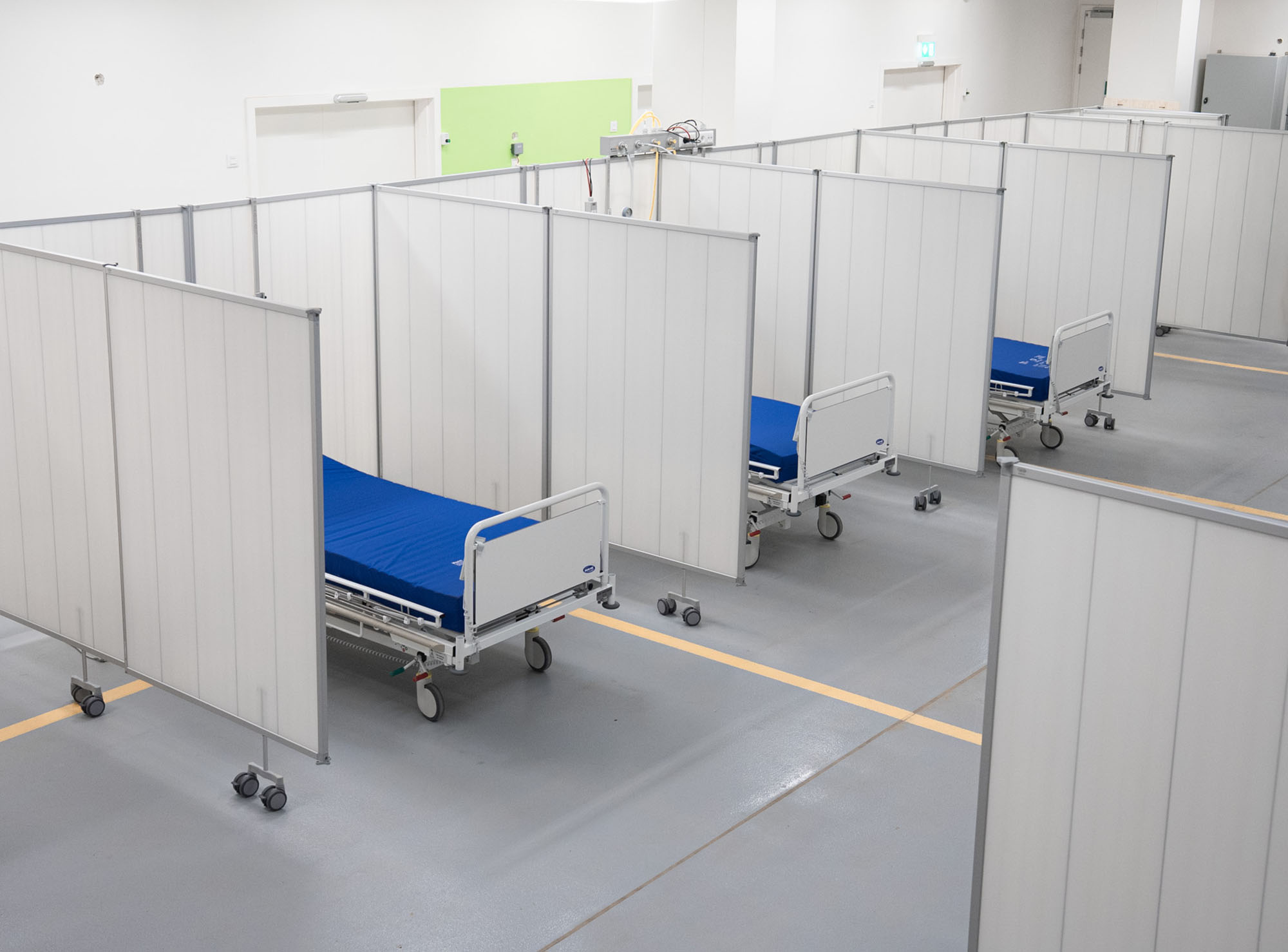 Silentia PopUp schermen verdelen een grote hal in afzonderlijke plekken met ziekenhuisbedden.