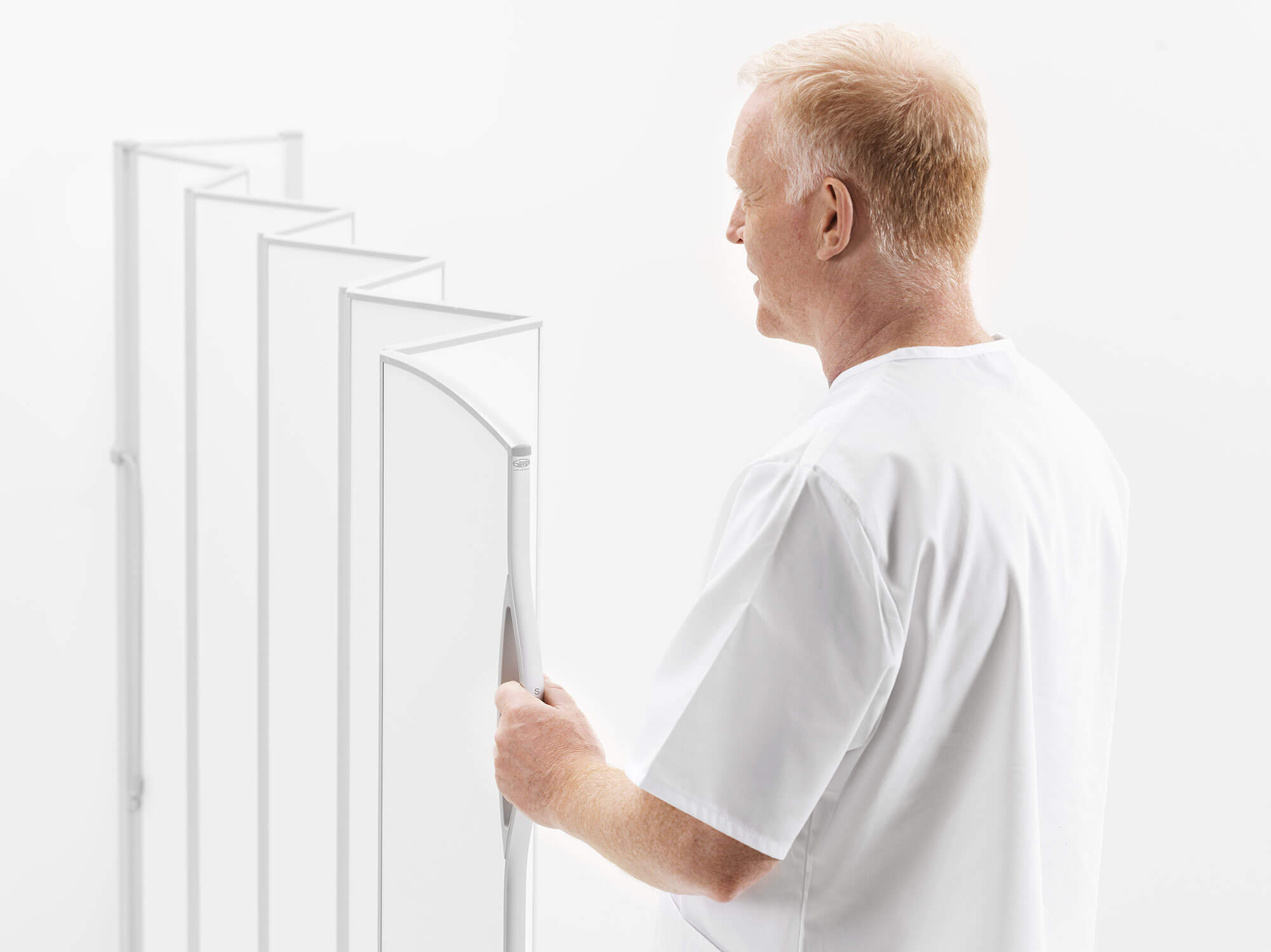 Care worker in white pulling open a white Silentia folding screen, inviting newsletter sign-up.